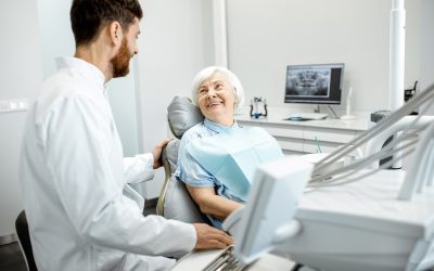 Beautiful elder woman with healthy smile sitting during the consultation with dentist at the dental office