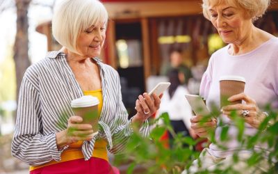 Two beautiful aged ladies having coffee and looking at their smartphones
