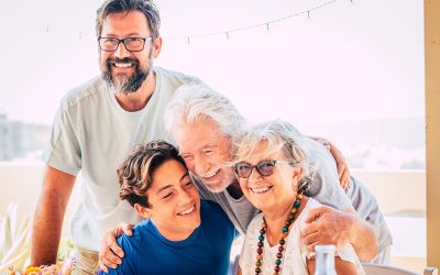 Happy mixed three generations family hug and enjoy together - people group portrait with seniod adult and teenager together - bright sky background and cheerful smiles