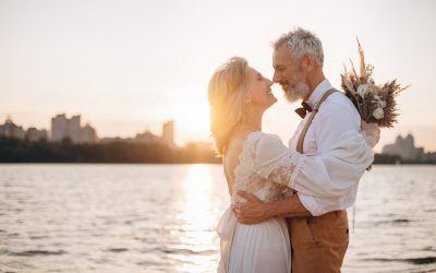 Happy elderly couple in wedding dress looking at each other in sun.