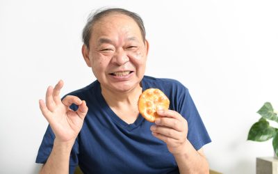 煎餅を持ちOKポーズをする高齢者男性