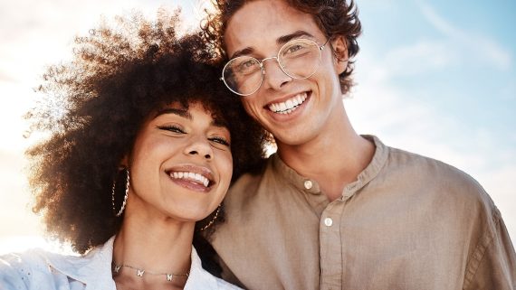 Portrait of a young mixed race couple enjoying a day at the beach looking happy and in love.