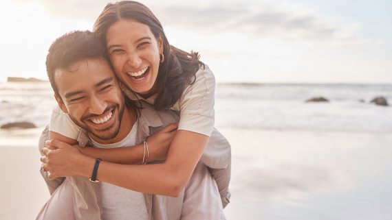 Couple, portrait and hug at the beach with happiness on vacation for love with sunshine. Man, woman and hugs at the ocean with sun for a holiday with a smile for the weekend with a relaxing date